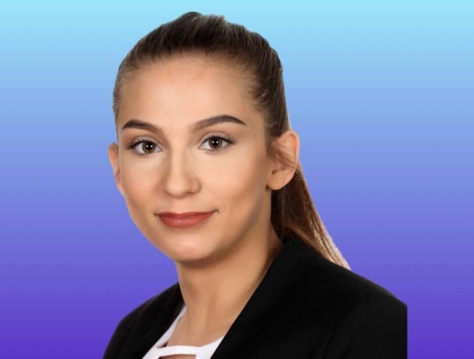 zdjęcie portretowe - bohaterka wywiadu, młoda kobieta patrzy przed siebie. Uśmiecha się. Ma długie, ciemne - zaczesane do tyłu włosy, odsłonięte uszy. Sylwetka uchwycona nieco z boku. Ma na sobie jasną bluzkę i ciemną marynarkę - z wycięciem w szpic